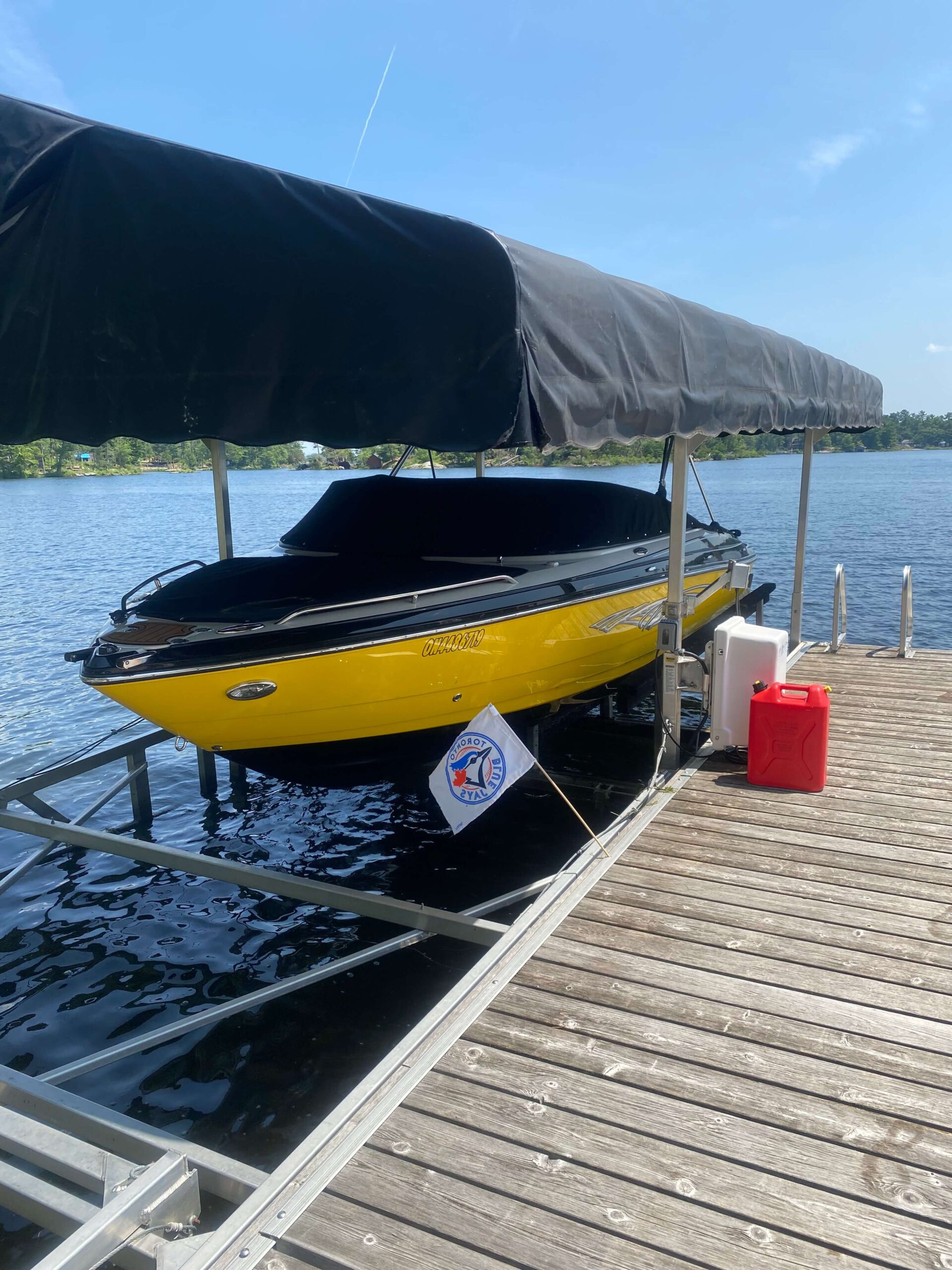 Wakeboard boat parked in a boatlift, elevated up off the water.