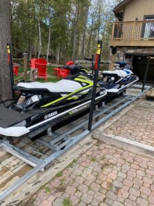 Two Sea-Doos docked on a metal railway on a property