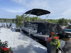 Pontoon docked on a boatlift next to a composite dock over water