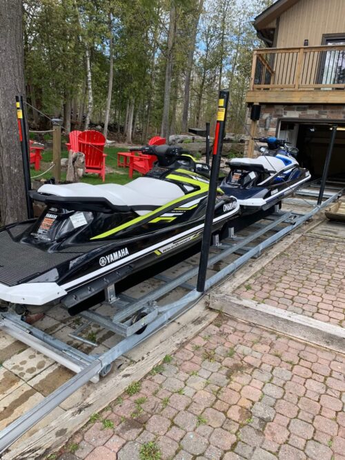 Two Sea-Doos docked on metal rails on a property