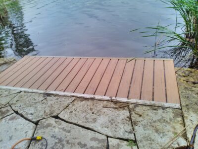 Wave X dock installed at the water's edge with interlocking stone framing it in