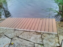 Wave X dock installed at the water's edge with interlocking stone framing it in