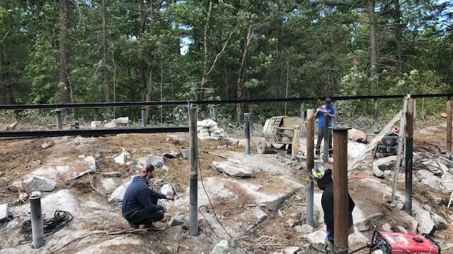 People placing metal posts in the ground