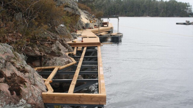 Wooden deck within rock formations next to a lake partially assembled