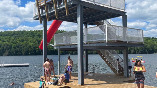 Tall platforms with stairs with waterslide on the water with people