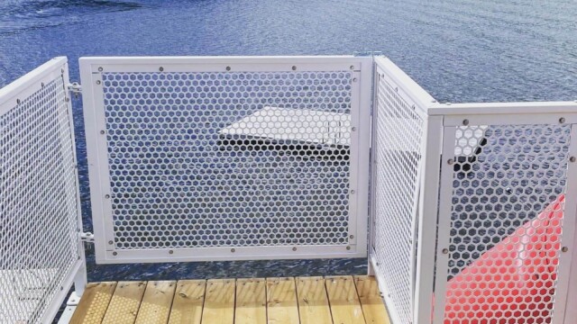 Metal railing attached to a wooden dock on a lake with trees