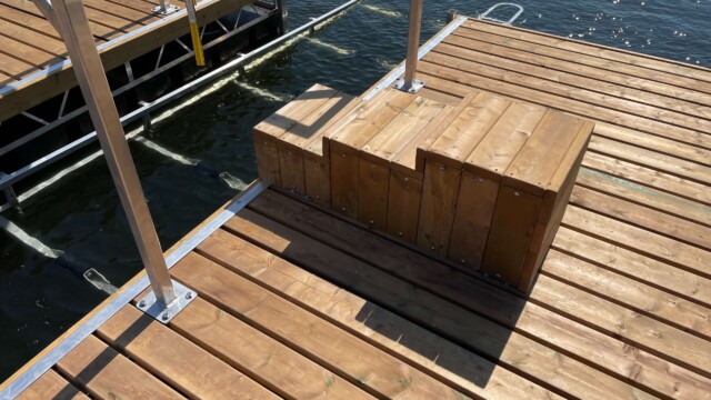 Wood dock and steps surrounding metal boat lift in a lake