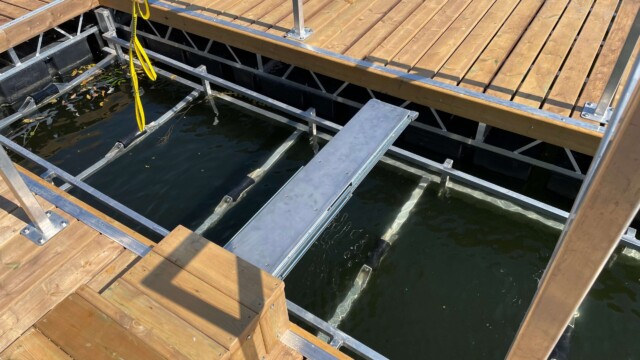 Metal boatlift in a lake surrounded by wooden dock